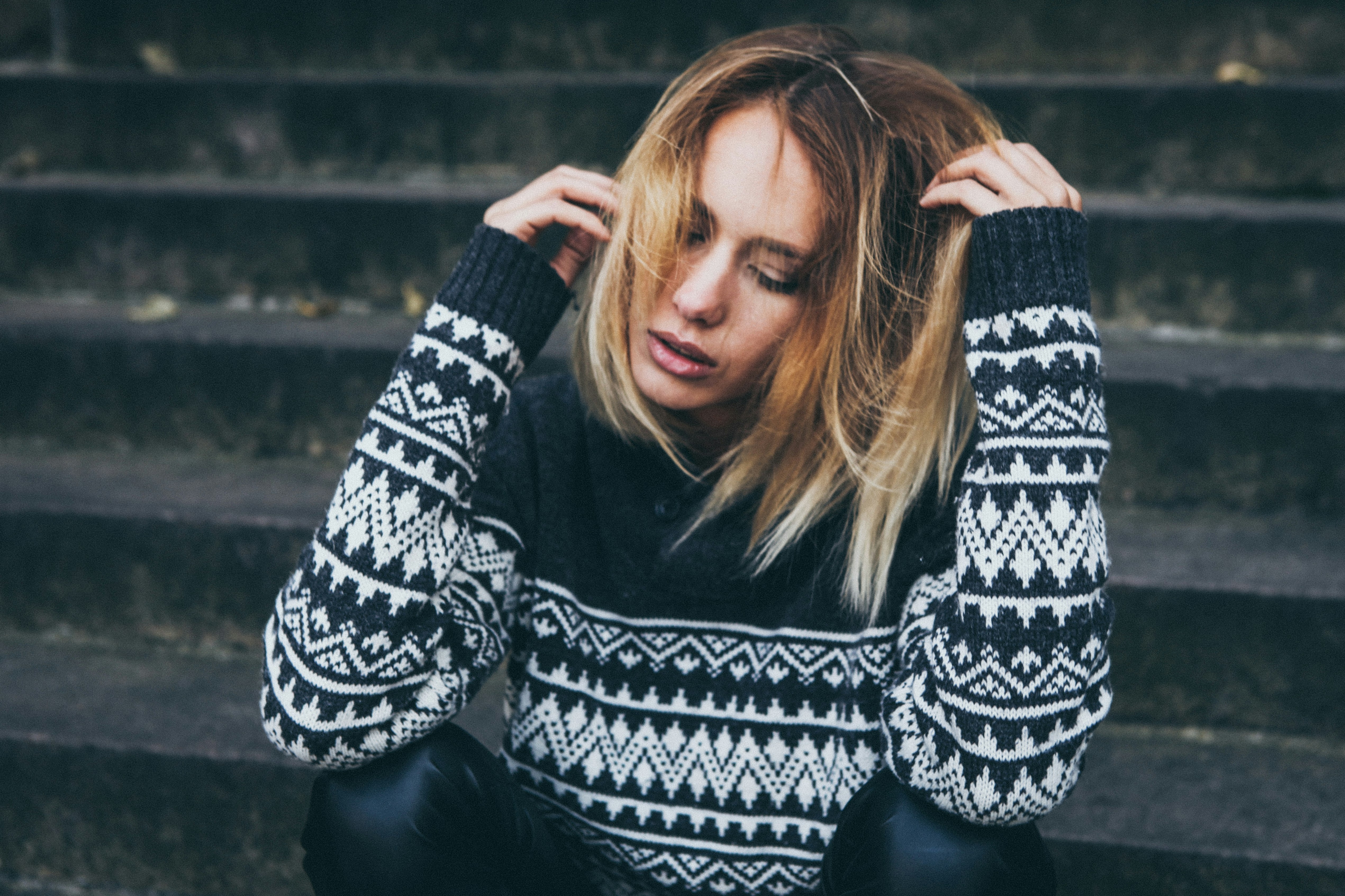 woman wearing white and black sweater sitting on stair